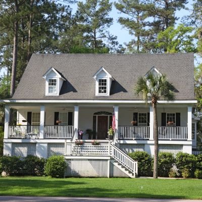 A charming white house in Okatie, South Carolina, featuring a welcoming porch with a railing.